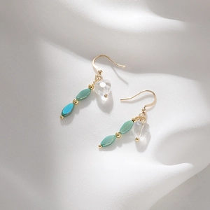 Elegant gold heart-shaped earrings with synthetic turquoise dangles on silk background