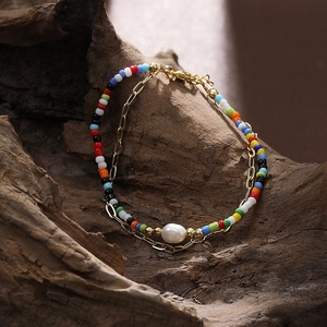 Bracciale boho a strati con perline colorate, catene dorate e una perla barocca naturale