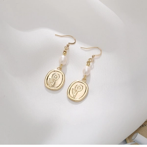 French vintage gold pearl earrings with sunflower relief pendant on silk background