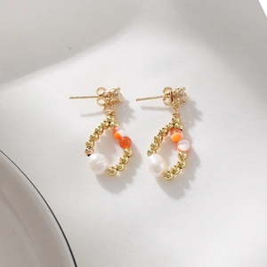 14K gold plated earrings with freshwater pearl, orange beads, and zircon studs on white cloth