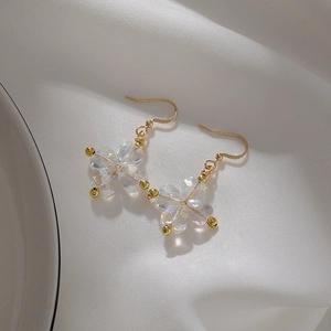 Boucles d'oreilles dorées avec pendentifs cœurs irisés sur tissu de soie blanc