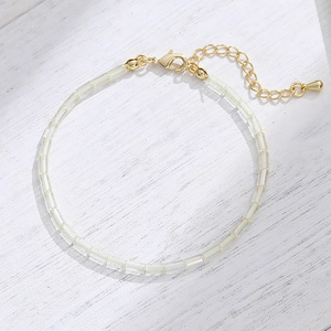 Double-layered gold chain bracelet with coin relief pendant and yellow beads on wood