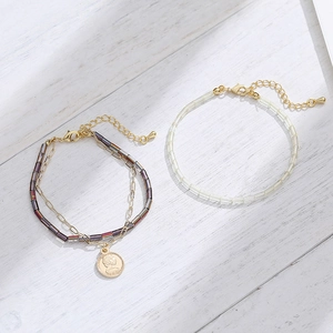 Double-layer beaded bracelet with vintage coin pendant on white wood background