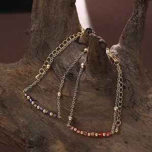 Bracelets dorés en acier inoxydable avec perles carrées colorées sur fond bois