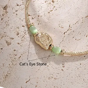 Golden pleated chain bracelet featuring light green cat eye stones and rock texture metal
