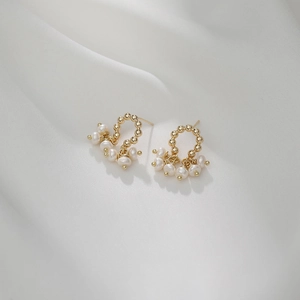Elegant gold curved stud earrings with white freshwater pearls on white silk fabric