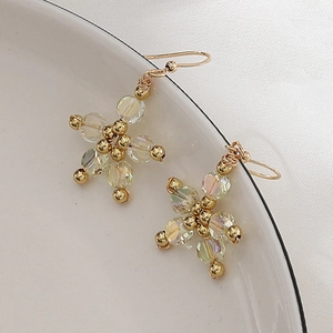 Vintage floral pendant earrings with iridescent beads and gold hooks on white ceramic