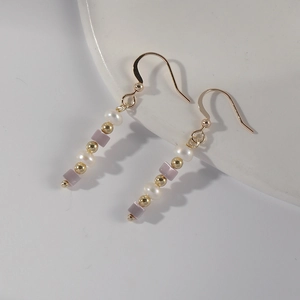 Detail of long beaded earrings with freshwater pearls and purple stones on gold hooks
