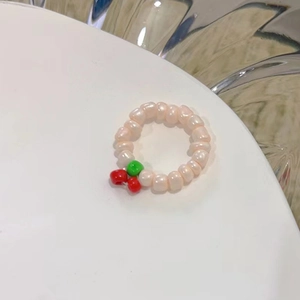 Primo piano dell'anello di perle bianche con un grazioso ciondolo a forma di ciliegia rossa