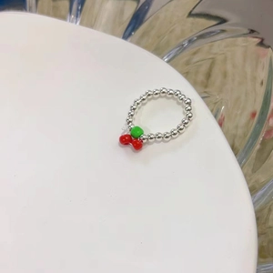 Dettaglio dell'anello fatto a mano con perle argentate e ciondolo a forma di ciliegia