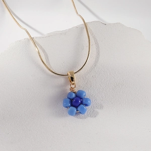 Collier chaîne serpent dorée avec pendentif fleur en perles sur socle en pierre