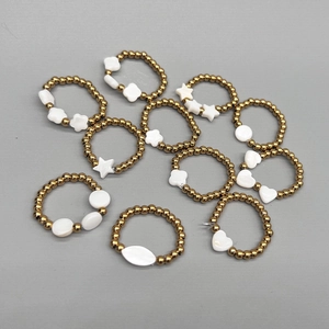 Close-up of 18K gold beaded elastic rings with natural freshwater shell charms