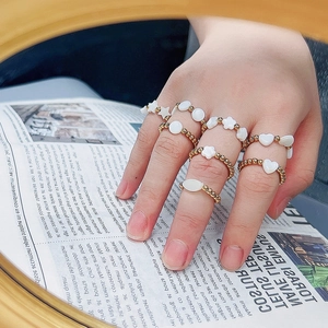 Stackable 18K gold beaded stainless steel rings with white shell charms on model hand