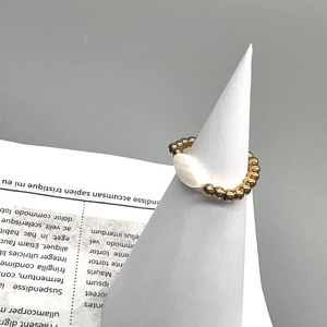 Detail of 18K gold beaded elastic ring featuring a white marquise-shaped shell inlay