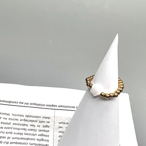 Close-up of 18K gold stainless steel beaded ring with a white clover shell pendant