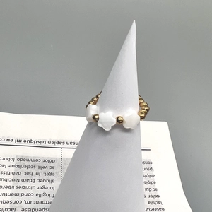 Detail of 18K gold stainless steel beaded ring featuring three white shell flowers