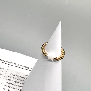 Detail of 18K gold beaded stainless steel ring with white shell star charm on a stand