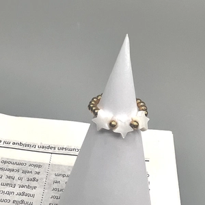 Detail view of gold beaded stretch ring featuring a natural shell star charm on cone stand