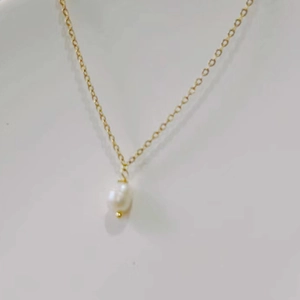 Detailed close-up of 14K gold plated titanium necklace with white teardrop pearl pendant