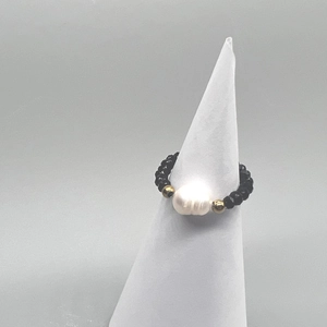 Macro view of elastic beaded ring featuring black faceted beads and a baroque pearl