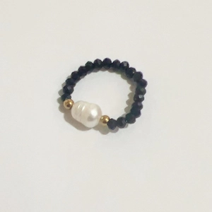 Macro view of handmade stretch ring with baroque pearl and black faceted beads