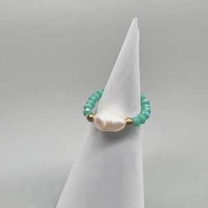 Detail view of elastic beaded ring featuring white baroque pearl and green faceted beads