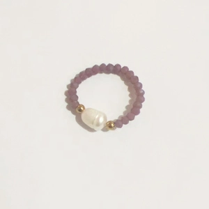 Macro view of elastic ring featuring a white freshwater pearl and purple frosted beads