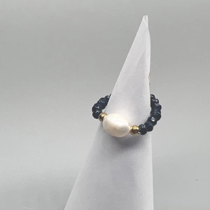 Detail of beaded stretch ring with blue faceted stones and a large baroque pearl center