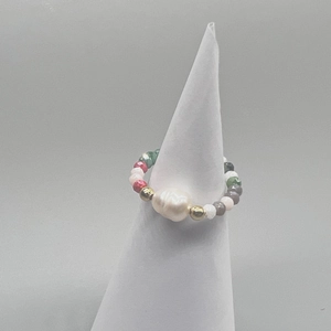 Macro detail of elastic beaded ring featuring a large baroque pearl and colorful glass beads