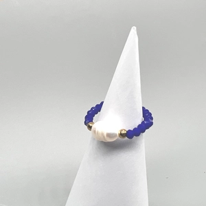 Detail of handmade elastic ring with blue faceted beads and a white baroque pearl focal
