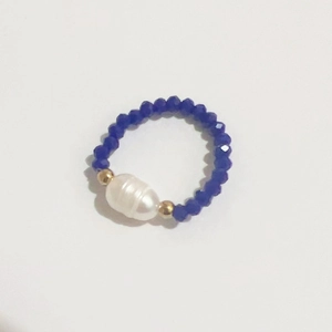 Macro detail of elastic bead ring featuring a white freshwater pearl and blue glass beads