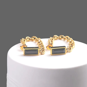 Gold chain drop earrings with emerald cut green zircon on white display stand