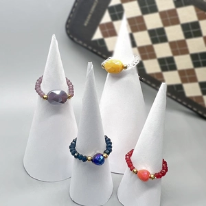 Colorful faceted crystal bead rings with center gemstone on white display stands