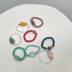 Top view of eight colorful beaded rings with large faceted crystal centerpieces