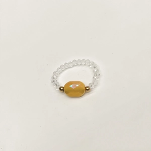 Macro view of elastic beaded ring featuring central yellow faceted olive bead
