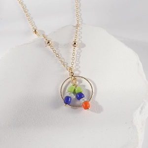 Gold beaded chain necklace featuring a circular pendant with colorful gemstone beads