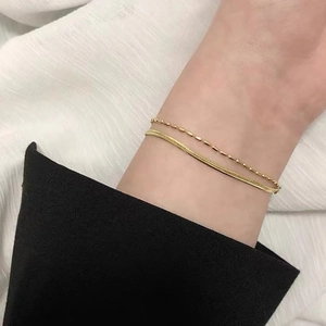 Zweilagiges, 18 Karat vergoldetes Schlangen- und Perlenarmband an einem Handgelenk