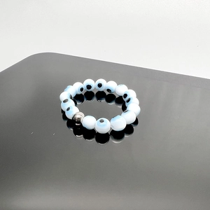 Macro detail of elastic Evil Eye beaded ring with blue nazar beads and silver metal accent