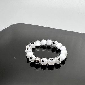 Macro detail of elastic beaded ring featuring evil eye charms and silver metal spacer bead