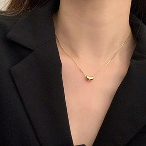 Minimalist gold bean pendant necklace for women shown on a professional model outfit