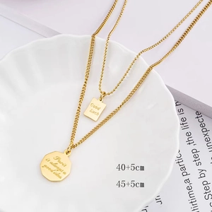Double-layered 18K gold plated titanium necklace with Good Luck pendants in a ceramic dish