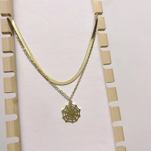 Layered gold snake chain necklace featuring a unique spider web pendant design