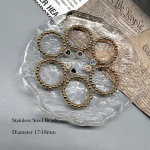 Set of 6 gold beaded rings with colorful heart-shaped zirconia charms on a glass tray