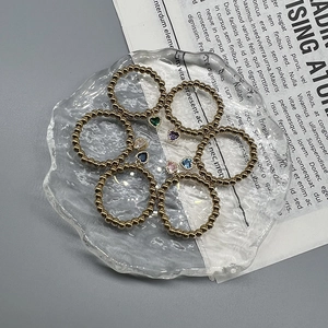 Detail of six gold bead elastic rings featuring multicolored heart-shaped crystal charms