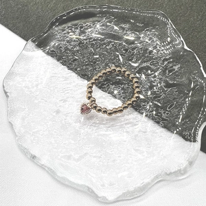 Detail of gold beaded stretch ring with a pink heart-shaped crystal pendant