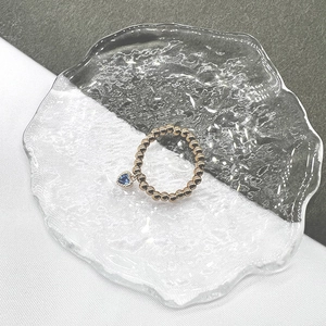 Macro detail of elastic beaded ring with heart-shaped blue zircon charm in gold finish
