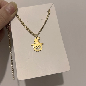 Detailed view of Halloween pumpkin ghost charm on a golden Figaro chain necklace