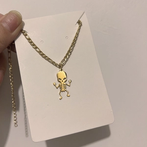 Macro view of gold skeleton charm on Figaro chain stainless steel necklace