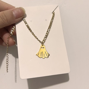 Close-up of gold ghost pendant on Figaro chain for Halloween jewelry collection