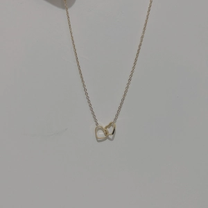 Détail de pendentifs en forme de cœur creux imbriqués sur une fine chaîne dorée